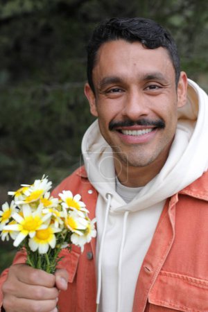 Foto de Retrato del guapo hombre hispano con bigote sosteniendo ramo de manzanillas - Imagen libre de derechos