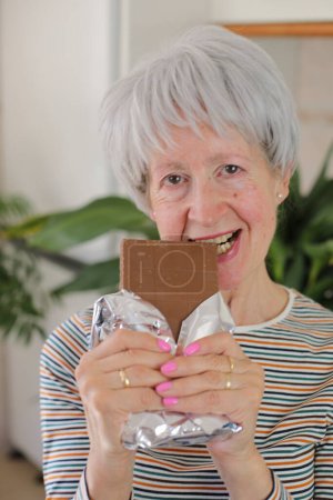 Téléchargez les photos : Portrait d'une femme mûre aux cheveux gris tenant du chocolat au lait à la maison - en image libre de droit