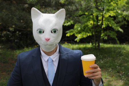 Téléchargez les photos : Homme d'affaires avec un visage de chat sur fond de nature - en image libre de droit