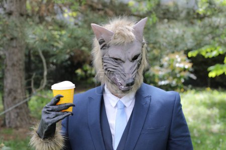 Foto de Empresario con cara de lobo bebiendo un café sobre fondo natural - Imagen libre de derechos