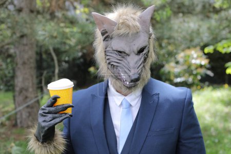 Photo for Businessman with a wolf face drinking a coffee on nature background - Royalty Free Image