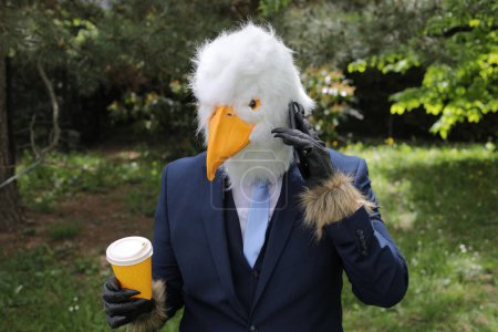 Téléchargez les photos : Homme d'affaires avec un visage d'aigle faisant un appel téléphonique - en image libre de droit