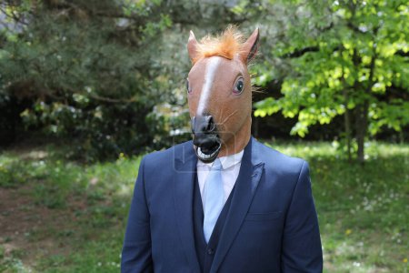 Téléchargez les photos : Homme d'affaires avec un visage de cheval sur fond de nature - en image libre de droit