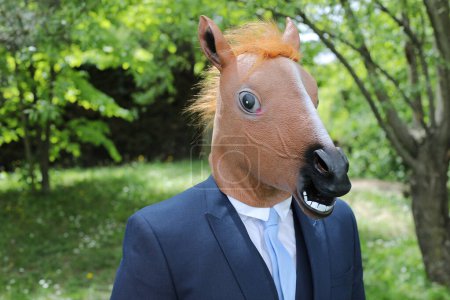 Téléchargez les photos : Homme d'affaires avec un visage de cheval sur fond de nature - en image libre de droit
