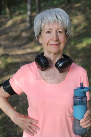 Téléchargez les photos : Femme active senior tenant une bouteille d'eau - en image libre de droit