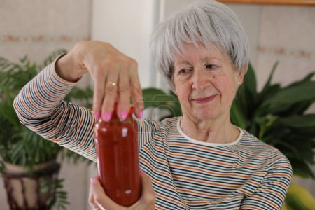 Foto de Mujer mayor tratando de abrir un frasco - Imagen libre de derechos