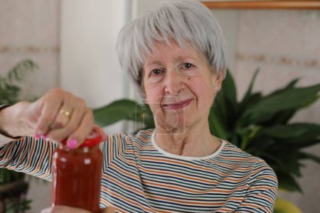 Foto de Mujer mayor tratando de abrir un frasco - Imagen libre de derechos