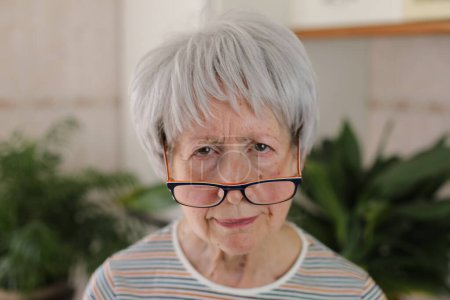 Senior woman squinting and putting her eyeglasses down