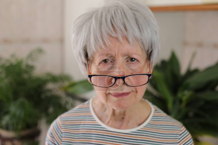 Foto de Mujer mayor entrecerrando los ojos y bajando las gafas - Imagen libre de derechos