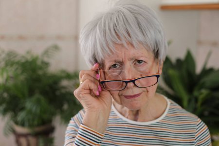 Senior woman squinting and putting her eyeglasses down