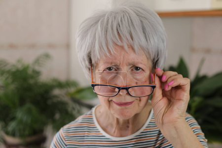 Mujer mayor entrecerrando los ojos y bajando las gafas