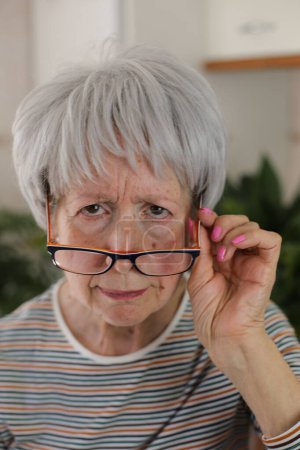 Téléchargez les photos : Senior femme plisser et mettre ses lunettes vers le bas - en image libre de droit