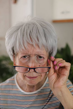 Téléchargez les photos : Senior femme plisser et mettre ses lunettes vers le bas - en image libre de droit