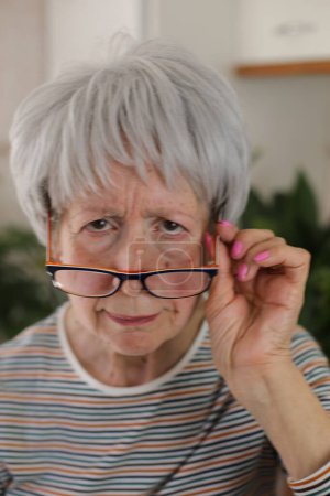 Senior femme plisser et mettre ses lunettes vers le bas
