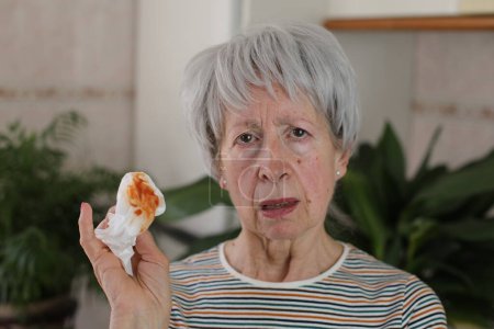 Téléchargez les photos : Femme âgée tousse de la salive avec du sang - en image libre de droit