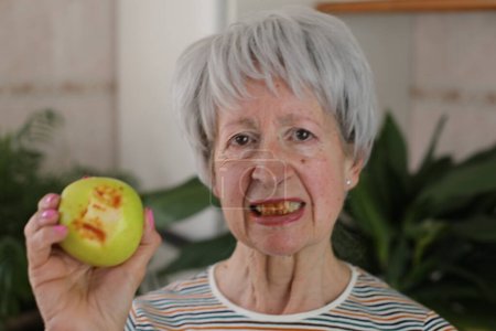 Senior woman with bloody gums after biting an apple