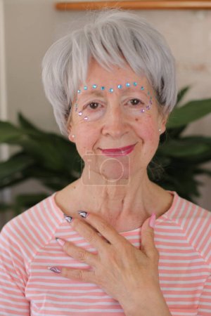 Seniorin trägt extravagante Edelsteine im Gesicht
