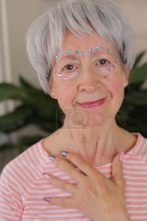 Senior woman wearing extravagant gemstones on face make up