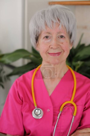 Foto de Enfermera senior vestida con bata rosa y estetoscopio amarillo - Imagen libre de derechos