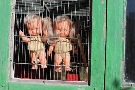 Téléchargez les photos : Poupées jumelles effrayantes regardant par la fenêtre - en image libre de droit