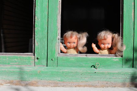 Foto de Espeluznantes muñecas gemelas mirando a través de la ventana - Imagen libre de derechos