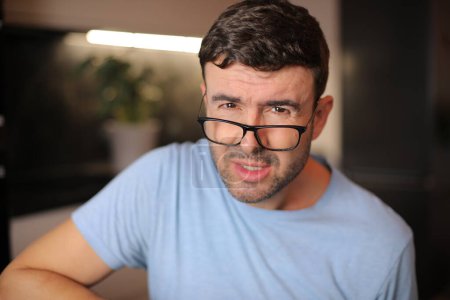 Man squinting and putting his eyeglasses down