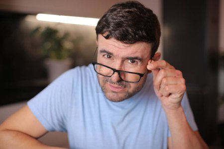 Man squinting and putting his eyeglasses down