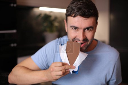 Téléchargez les photos : Homme affamé dégustant du chocolat - en image libre de droit