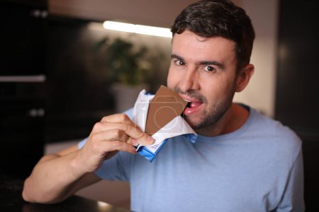 Téléchargez les photos : Homme affamé dégustant du chocolat - en image libre de droit