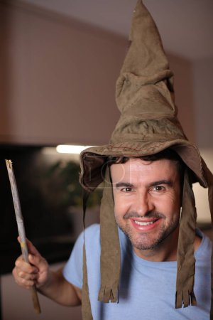 Téléchargez les photos : Homme portant un chapeau de sorcier et tenant une baguette magique - en image libre de droit