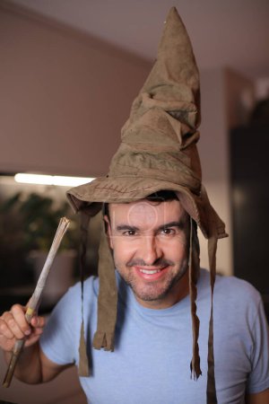 Téléchargez les photos : Homme portant un chapeau de sorcier et tenant une baguette magique - en image libre de droit