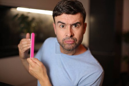 Photo for Judgmental looking man doing his nails - Royalty Free Image