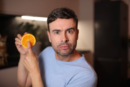Homme montrant l'intérieur des fruits orange
