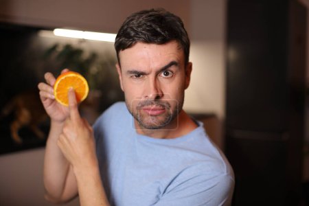 Téléchargez les photos : Homme montrant l'intérieur des fruits orange - en image libre de droit