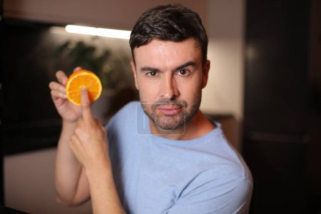 Téléchargez les photos : Homme montrant l'intérieur des fruits orange - en image libre de droit