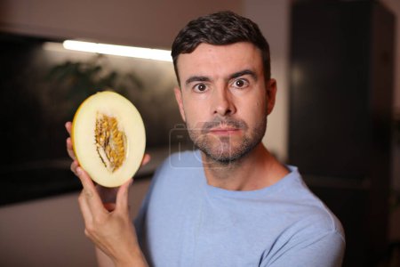 Téléchargez les photos : Homme montrant l'intérieur d'un fruit sur fond, gros plan - en image libre de droit