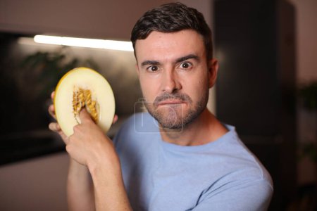 Téléchargez les photos : Homme montrant l'intérieur d'un fruit sur fond, gros plan - en image libre de droit