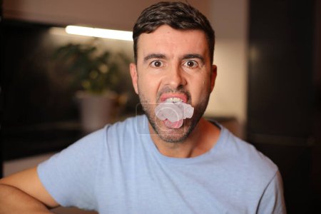 Mann hält Eiswürfel zwischen den Lippen