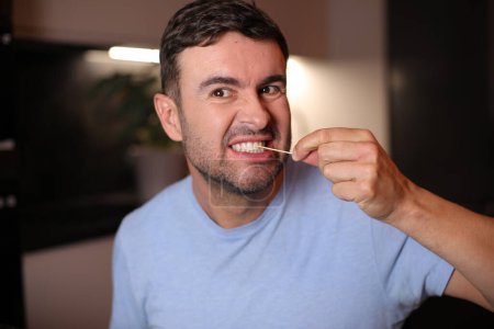 Hombre usando un palillo de dientes después del almuerzo en el fondo, de cerca