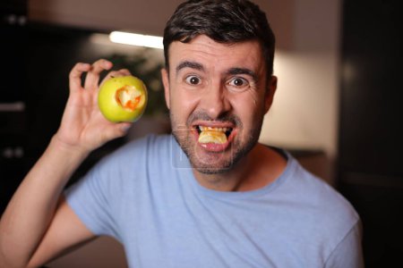 Man with bloody gums after biting an apple