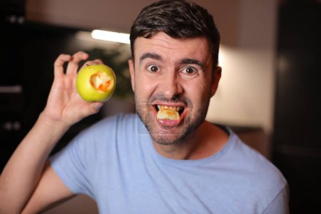 Man with bloody gums after biting an apple