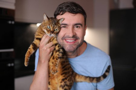 Foto de Lindo gato y su macho propietario en fondo, de cerca - Imagen libre de derechos