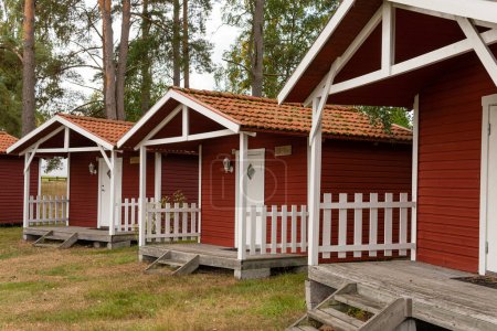 Téléchargez les photos : Petites maisons en bois rouge de style scandinave suédois près d'un terrain de golf. Logement vintage et confortable. Endroit idéal pour les introvertis. - en image libre de droit