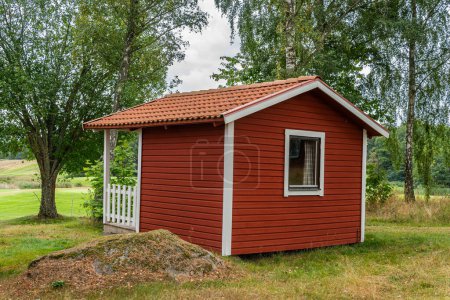 Foto de Pequeñas casitas de madera roja en estilo escandinavo sueco cerca de un campo de golf. Vintage, acogedora vivienda. Lugar ideal para introvertidos. - Imagen libre de derechos