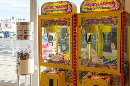 Foto de Suecia, Knislinge 16 de septiembre de 2022: Antigua máquina de juegos vintage en una tienda. Grúa de garra. Máquina de caramelos y encías de burbuja. Gran dispensador de caramelos, banco de gomitas, dispensador de gomitas. Entretenimiento para niños. - Imagen libre de derechos