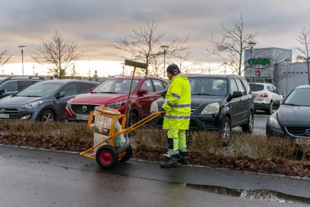 Foto de Suecia, Knislinge enero 3, 2023: Un hombre de uniforme recogiendo basura, limpiando calles. Scavenger, basurero, recolector de basura, ashman. - Imagen libre de derechos