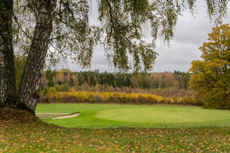 Foto de Campo de golf durante el otoño. Hermosa naturaleza, hierba verde y árboles multicolores. Símbolo del otoño. - Imagen libre de derechos