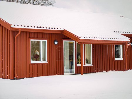 Foto de Antigua casa de madera roja en estilo escandinavo vintage en invierno. Antigua casa tradicional de Suecia en el pueblo. Clima nevado. - Imagen libre de derechos
