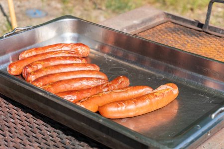 Foto de Grandes salchichas deliciosas se asan al aire libre en un cálido día soleado - Imagen libre de derechos