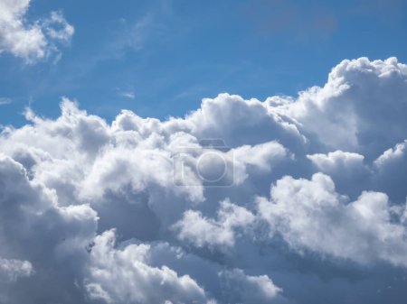 Téléchargez les photos : Vue sur le ciel bleu avec des nuages blancs moelleux par une journée ensoleillée. Fond de ciel sombre ensoleillé avec de beaux nuages blancs - en image libre de droit